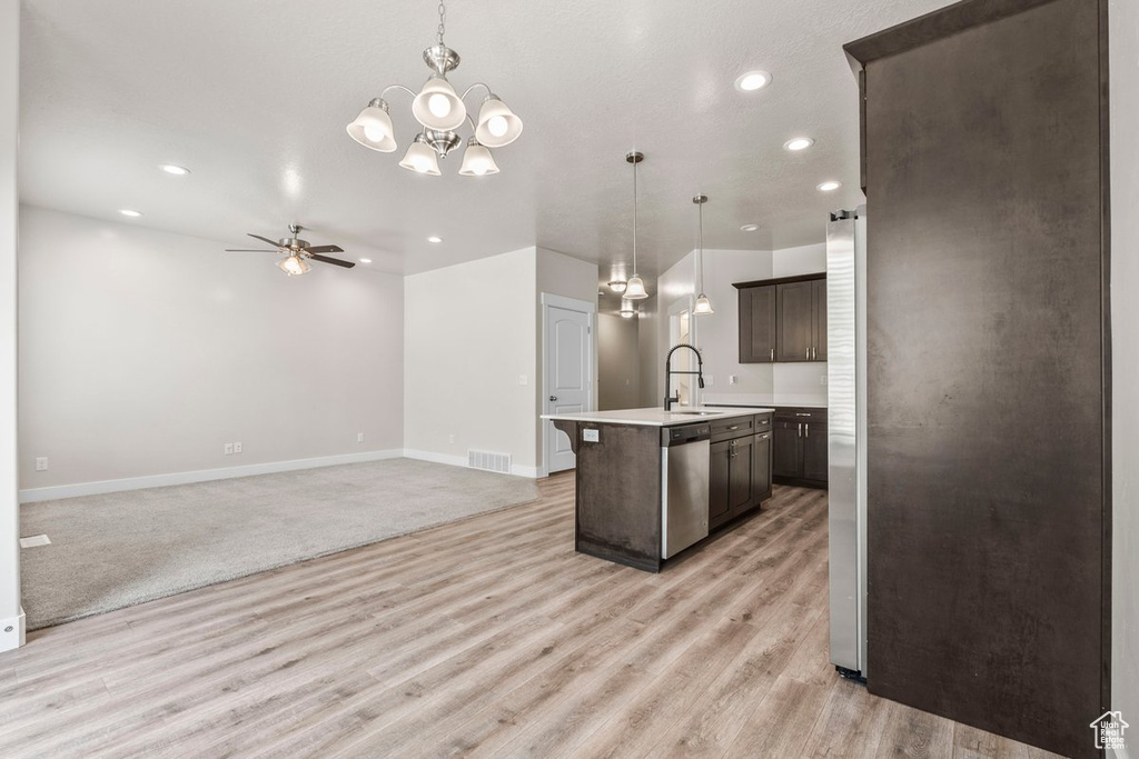 Kitchen with stainless steel appliances, light countertops, dark brown cabinetry, an island with sink, and light wood-style flooring