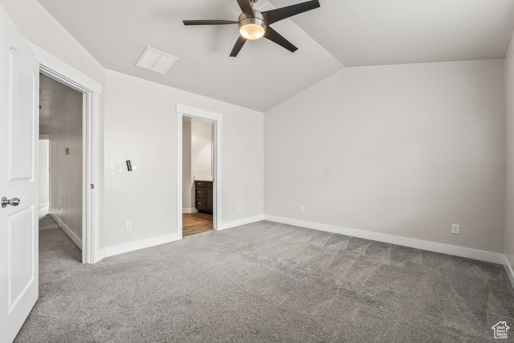 Unfurnished bedroom featuring carpet floors, lofted ceiling, baseboards, ensuite bathroom, and a ceiling fan