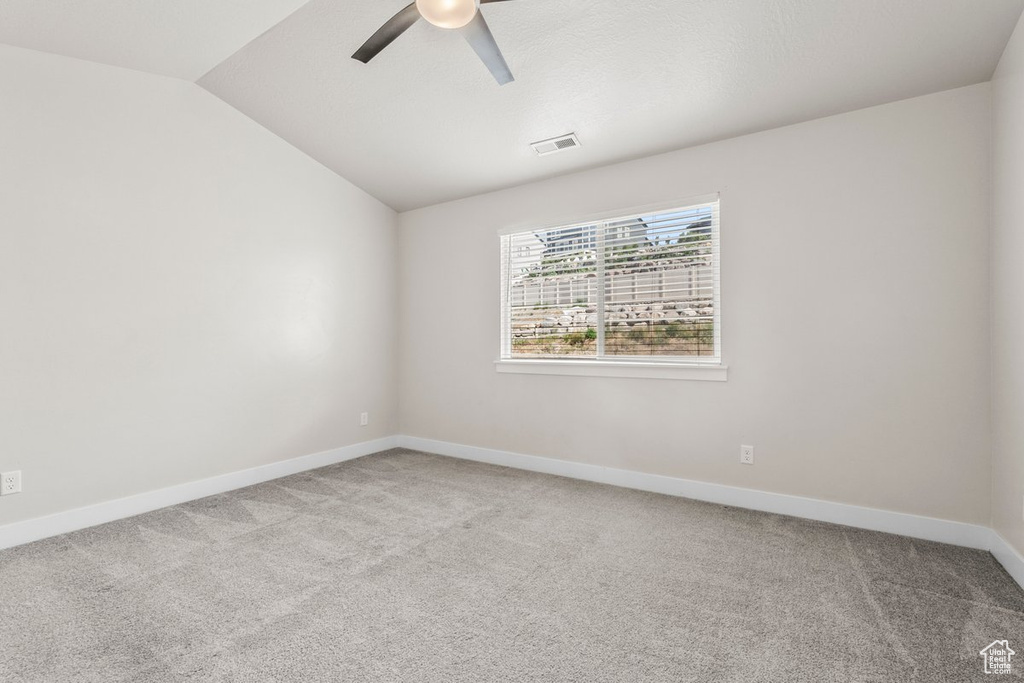 Unfurnished room featuring light carpet, ceiling fan, lofted ceiling, and baseboards
