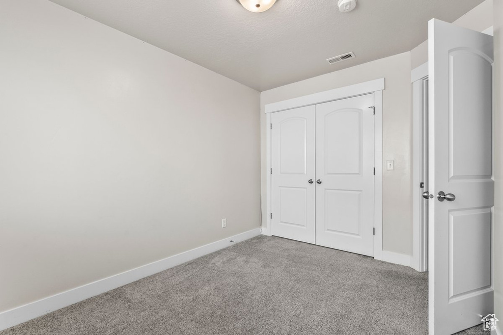 Unfurnished bedroom featuring carpet floors, baseboards, and a closet