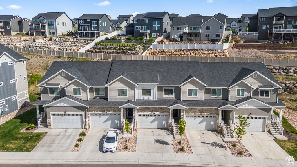 View of front of home featuring a residential view, driveway, roof with shingles, and a garage