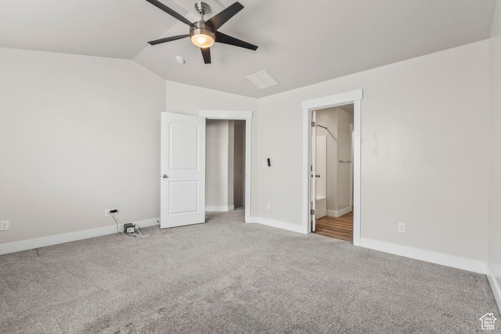Unfurnished bedroom with carpet, baseboards, lofted ceiling, a ceiling fan, and connected bathroom