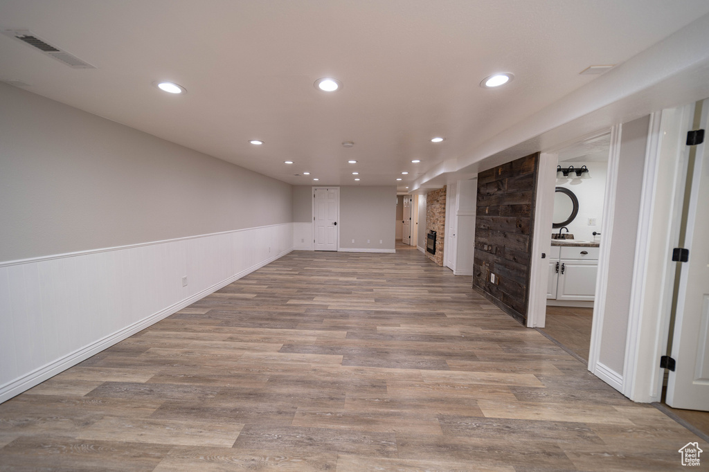 Finished below grade area with recessed lighting, wood finished floors, wainscoting, and a sink