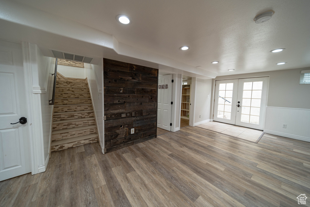 Unfurnished living room featuring french doors, wood finished floors, stairs, baseboards, and recessed lighting