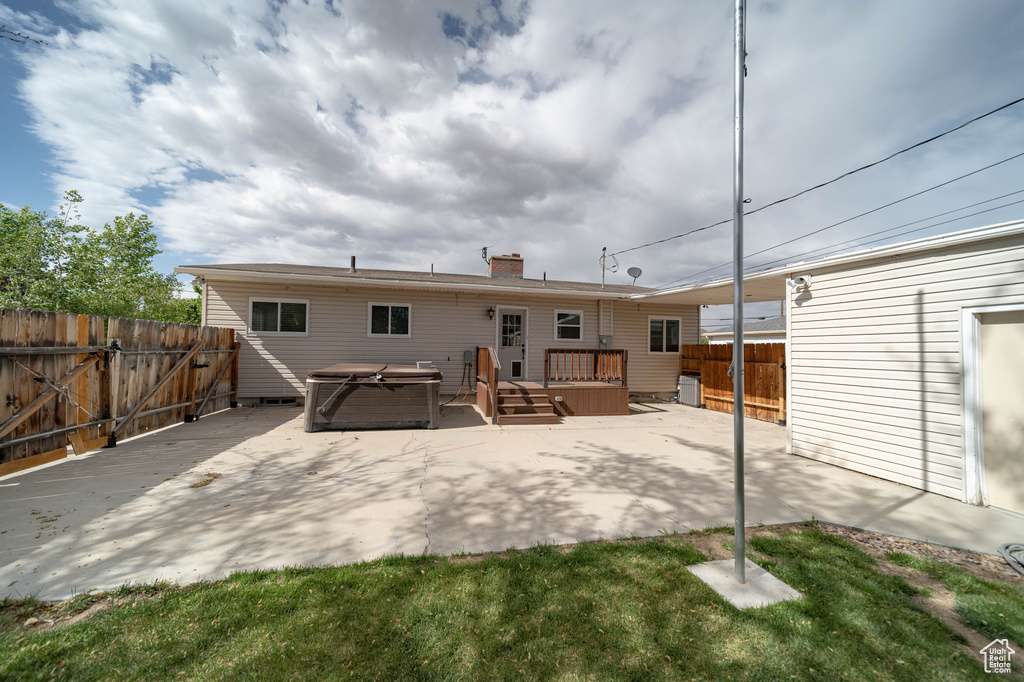 Rear view of property with a hot tub, a fenced backyard, and a patio