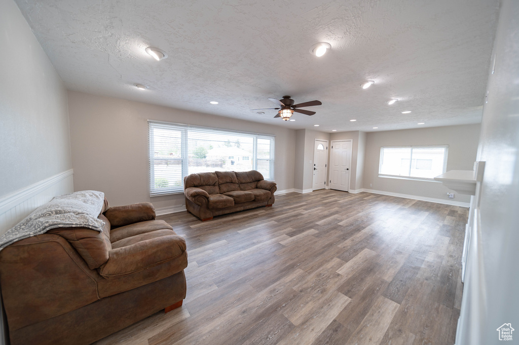 Living area featuring ceiling fan, wood finished floors, a textured ceiling, recessed lighting, and baseboards