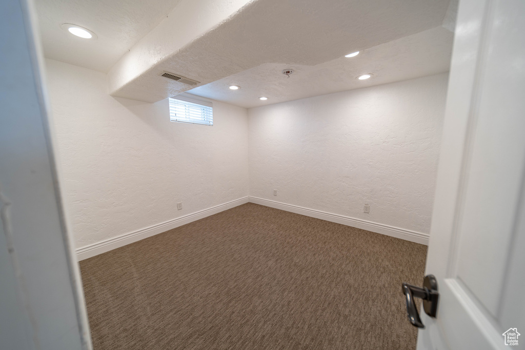 Below grade area featuring carpet, a textured wall, recessed lighting, and baseboards