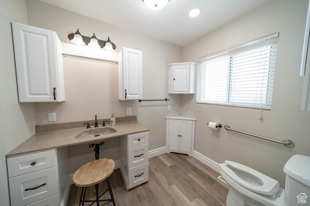 Bathroom featuring toilet, wood finished floors, baseboards, and vanity