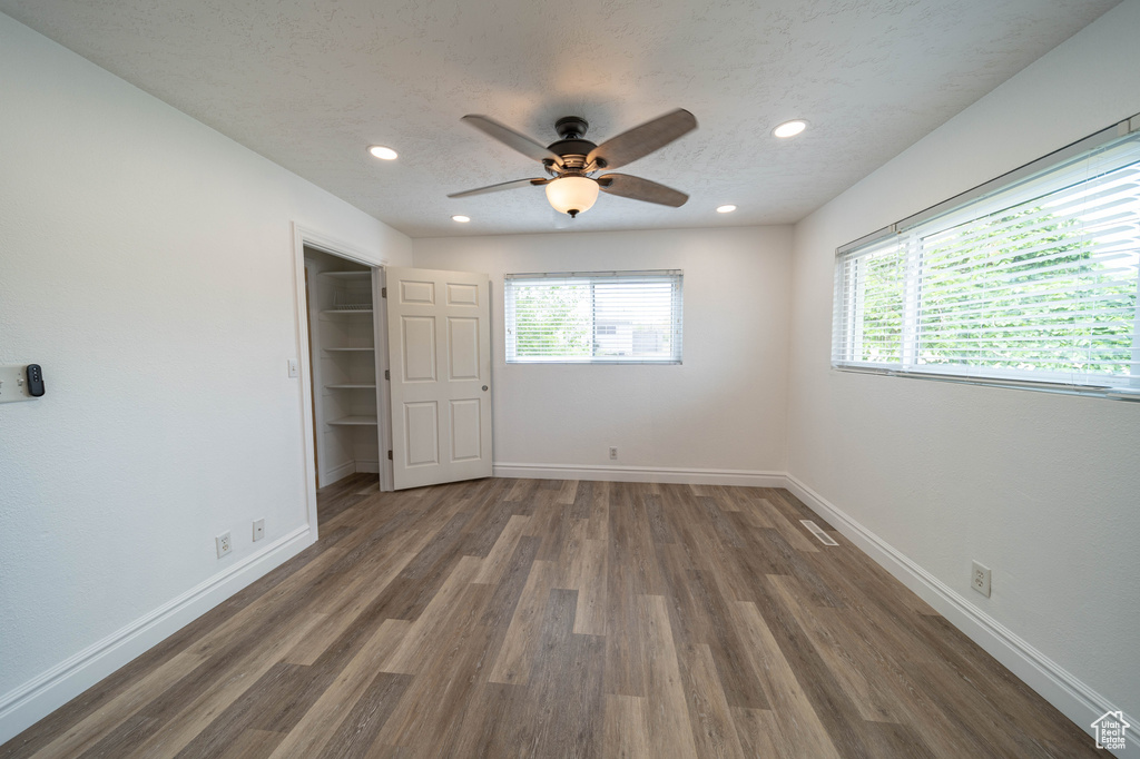 Unfurnished bedroom with multiple windows, wood finished floors, baseboards, and recessed lighting