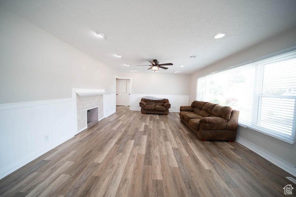 Living area featuring wood finished floors, ceiling fan, baseboards, a fireplace, and recessed lighting