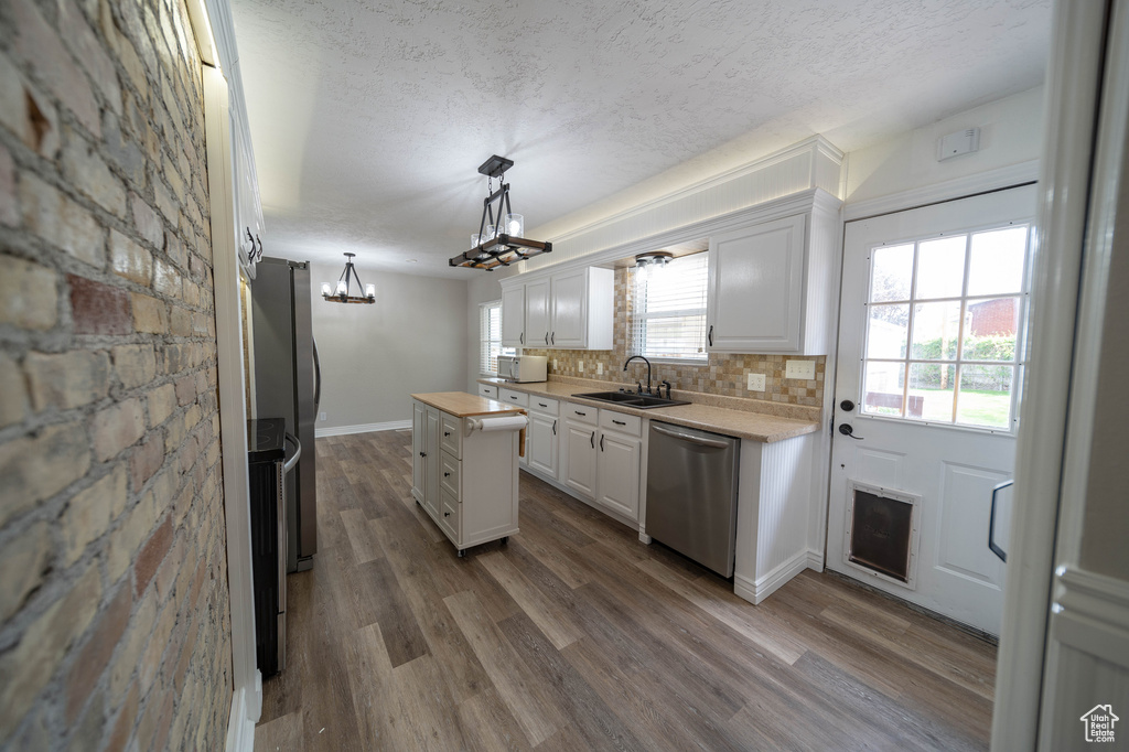 Kitchen featuring appliances with stainless steel finishes, a sink, a textured ceiling, white cabinets, and dark wood-style flooring
