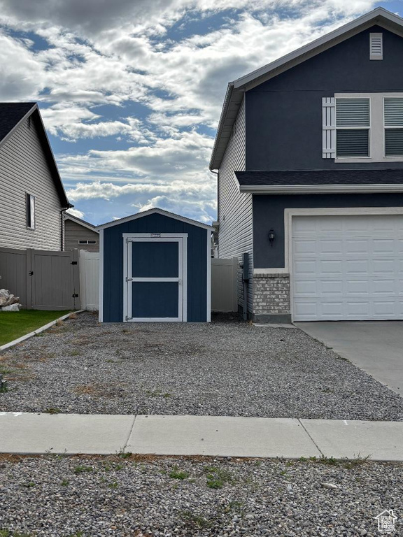 View of front of house with a shed, a gate, fence, and driveway