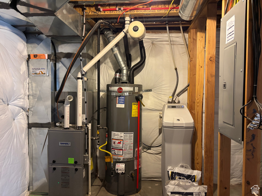Utility room featuring gas water heater, electric panel, and heating unit