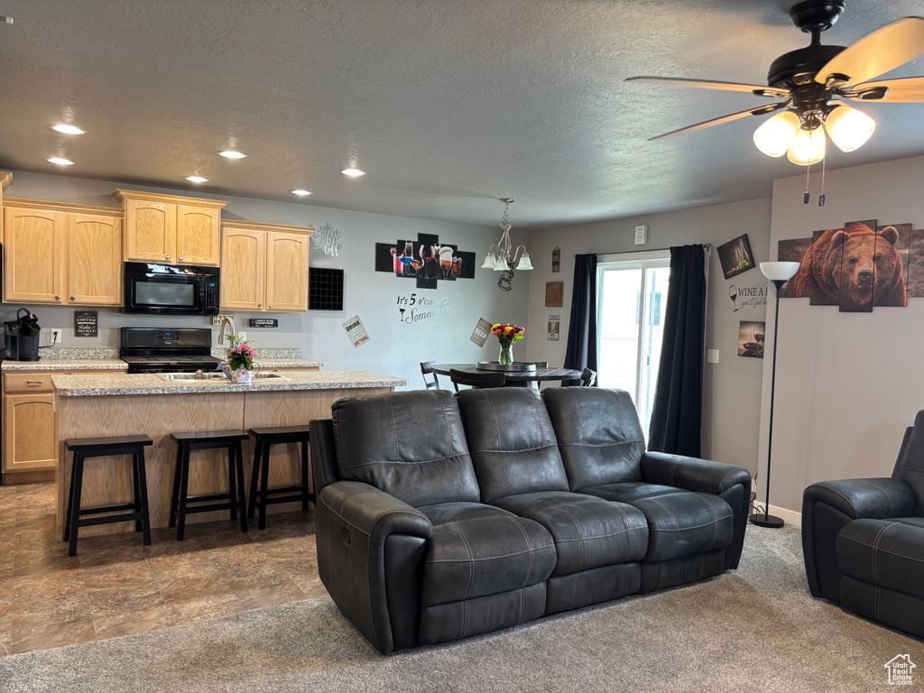 Living room with a textured ceiling, ceiling fan, and recessed lighting