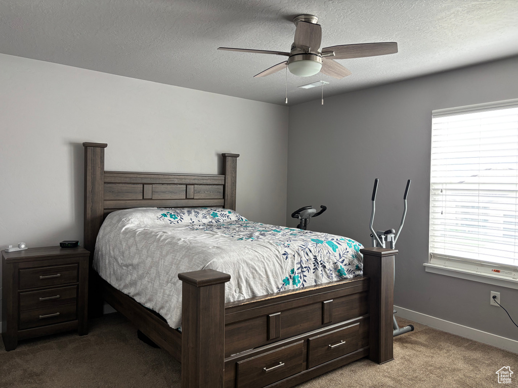 Carpeted bedroom featuring a textured ceiling, baseboards, and ceiling fan