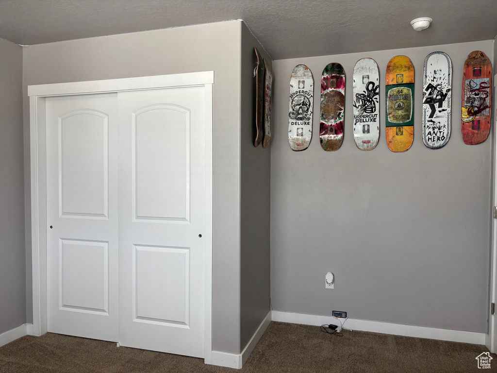 Unfurnished bedroom with dark colored carpet, baseboards, and a closet