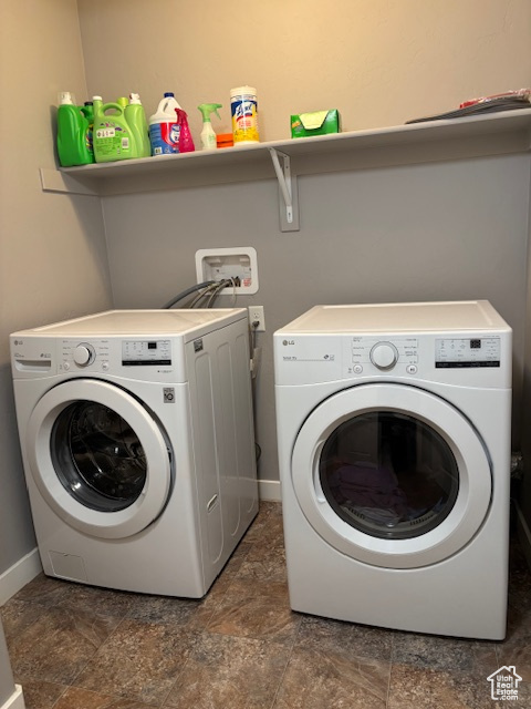 Laundry area featuring washer and dryer, stone finish floors, and baseboards