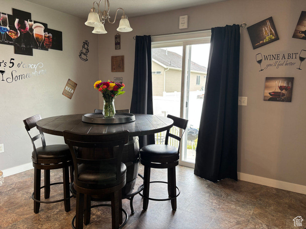 Dining area featuring baseboards, a chandelier, and dark stone finish flooring