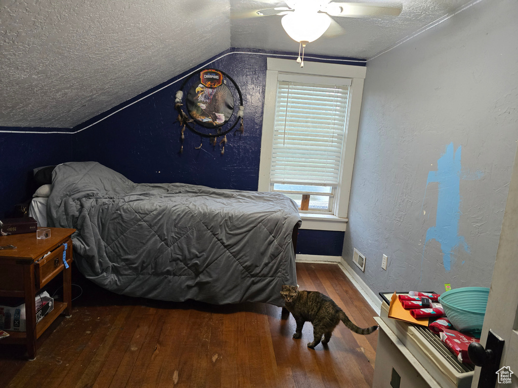 Bedroom featuring hardwood / wood-style floors, a textured ceiling, vaulted ceiling, multiple windows, and baseboards