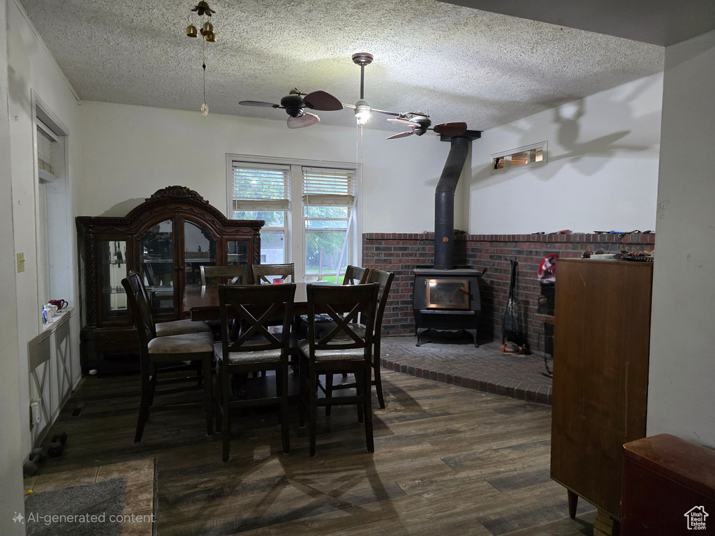Dining space with ceiling fan, a wood stove, a textured ceiling, and wood finished floors