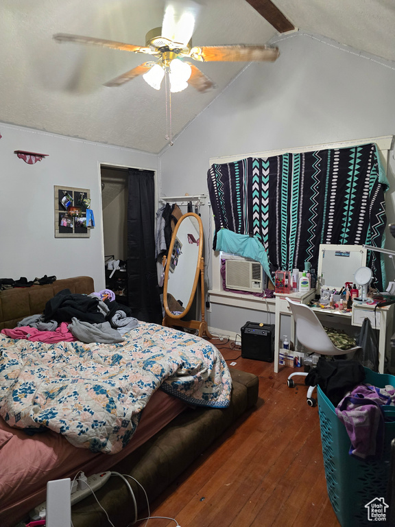 Bedroom featuring vaulted ceiling, wood-type flooring, cooling unit, ceiling fan, and a closet