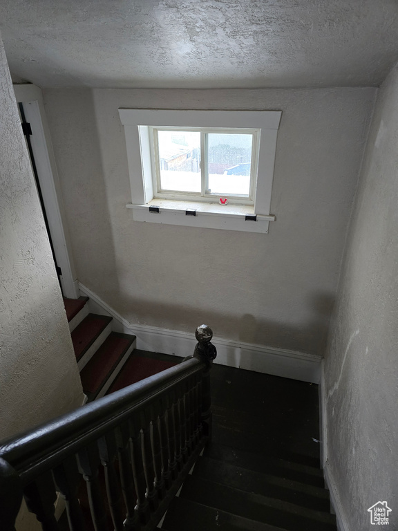 Stairs featuring wood finished floors and a textured ceiling