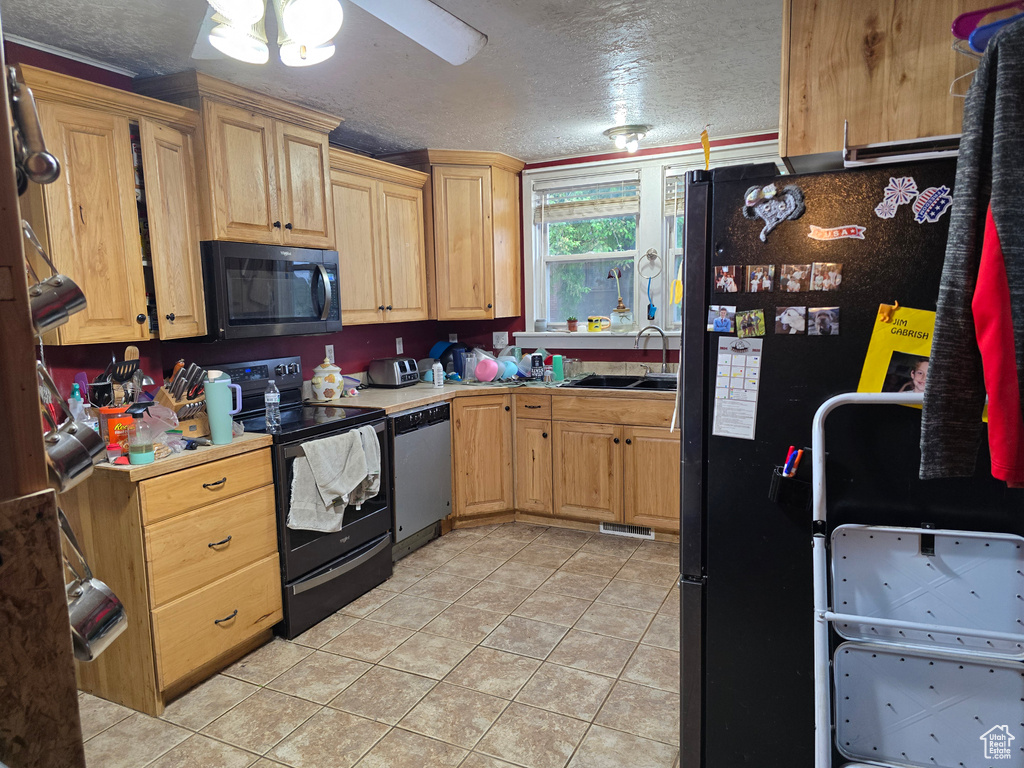 Kitchen featuring black appliances, a sink, a textured ceiling, light tile patterned flooring, and a ceiling fan