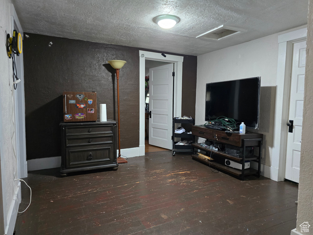 Living area with attic access, hardwood / wood-style flooring, a textured ceiling, and a textured wall