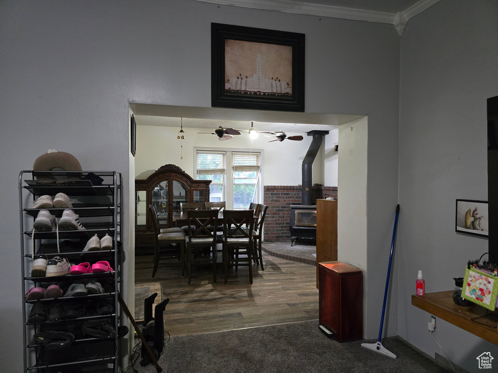 Carpeted dining space featuring a wood stove, ornamental molding, and wood finished floors