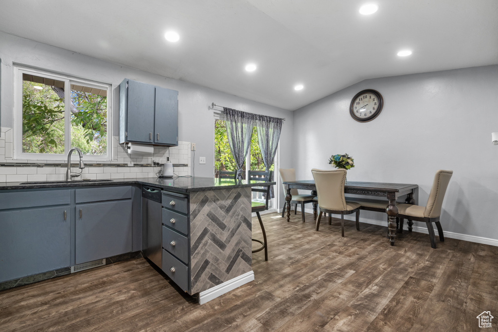Kitchen with a sink, a peninsula, decorative backsplash, lofted ceiling, and stainless steel dishwasher