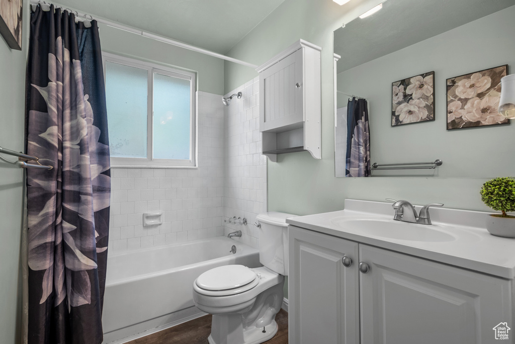 Bathroom with toilet, vanity, shower / tub combo, and wood finished floors