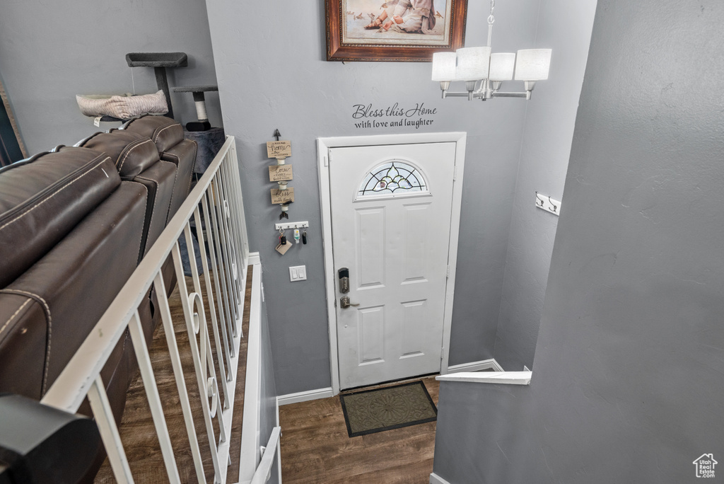 Foyer with dark wood-style flooring, a chandelier, and baseboards
