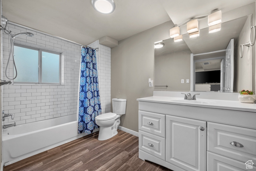 Full bath with toilet, vanity, shower / bath combo with shower curtain, and wood finished floors