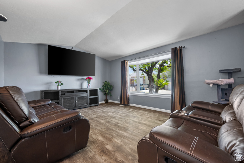 Living area featuring lofted ceiling, wood finished floors, and baseboards