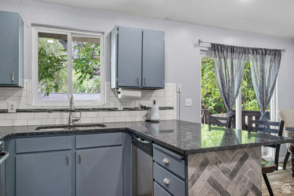 Kitchen featuring a sink, gray cabinetry, backsplash, and dishwasher