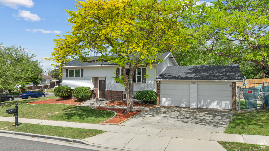 Split foyer home featuring brick siding, a garage, and driveway