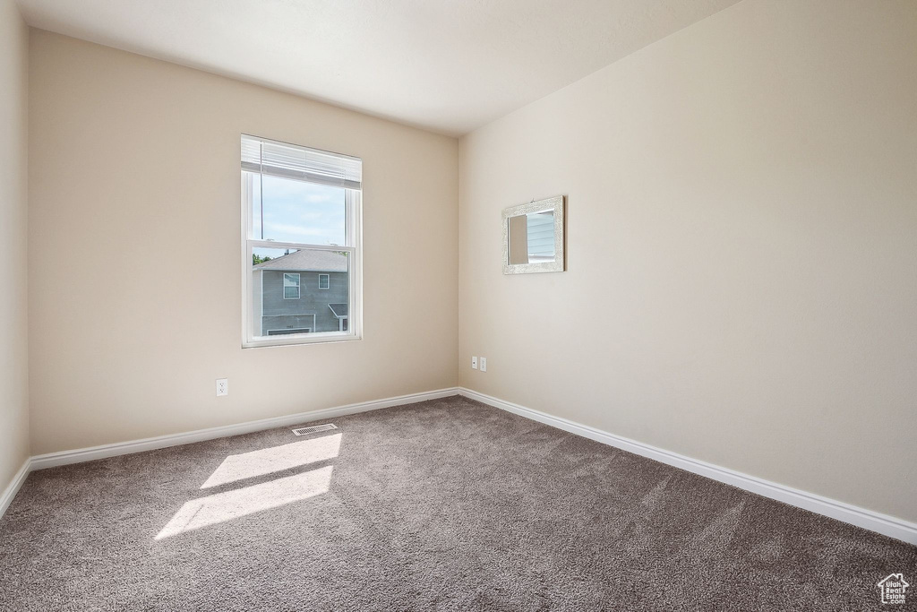 Carpeted spare room featuring baseboards