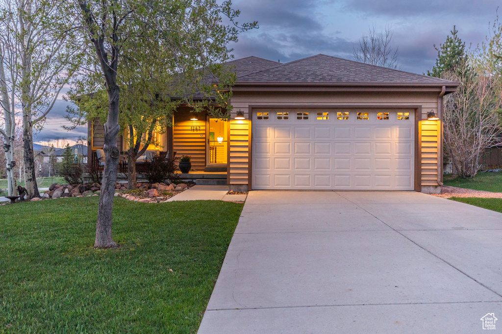 Ranch-style house with driveway, a front yard, a garage, and a shingled roof