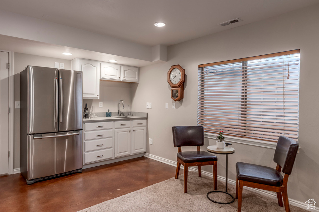 Kitchen featuring freestanding refrigerator, a sink, baseboards, white cabinetry, and recessed lighting