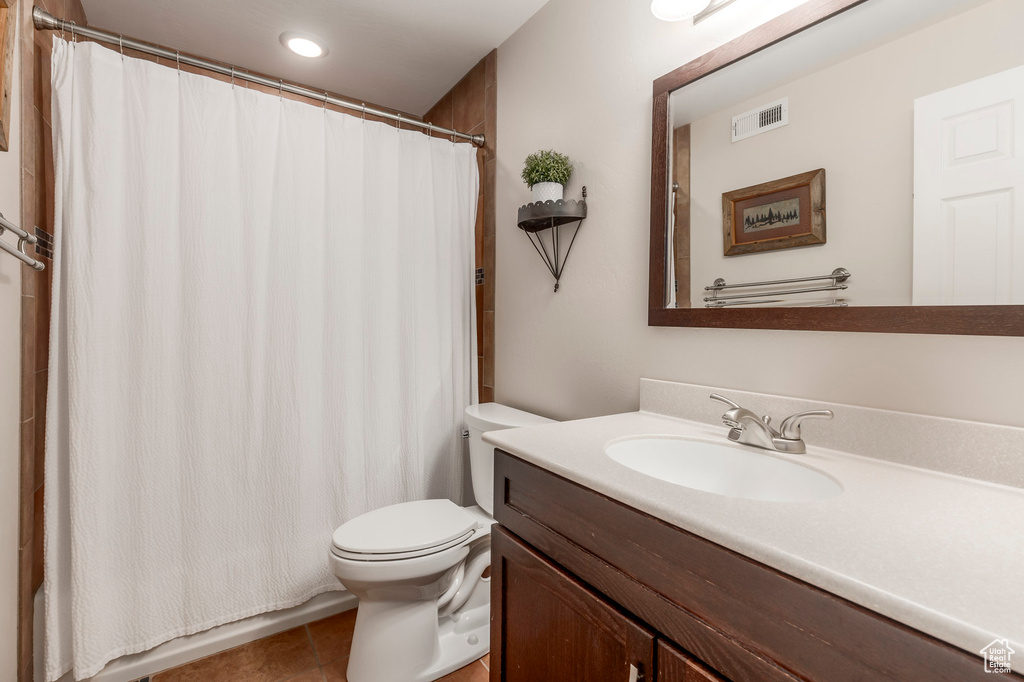 Bathroom featuring toilet, vanity, tile patterned flooring, and curtained shower