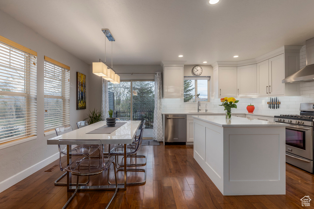 Kitchen with stainless steel appliances, a kitchen island, a sink, light countertops, and decorative backsplash