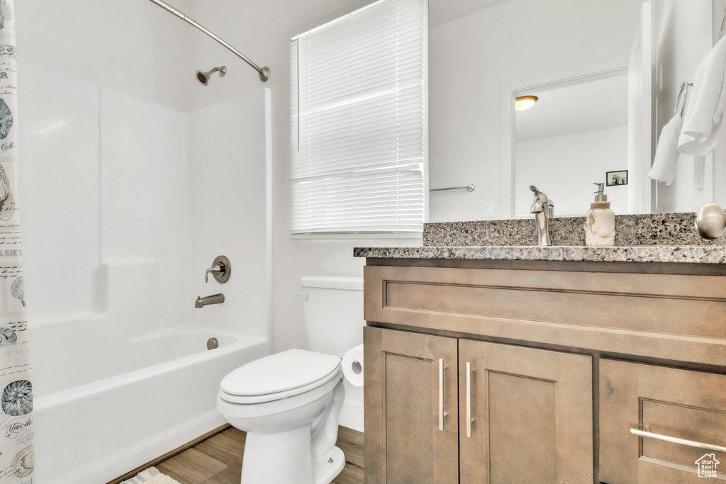 Bathroom featuring wood finished floors, toilet, vanity, and shower / bath combo with shower curtain