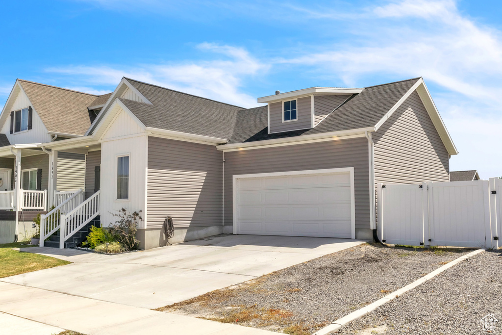 View of front of house featuring concrete driveway, an attached garage, a shingled roof, and fence