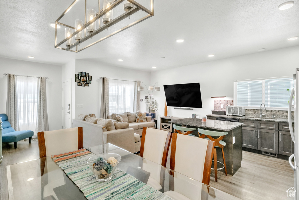 Dining area featuring light wood-style flooring, recessed lighting, and a textured ceiling