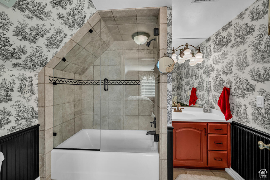 Full bath featuring wallpapered walls, a wainscoted wall, shower / bath combination with glass door, and vanity