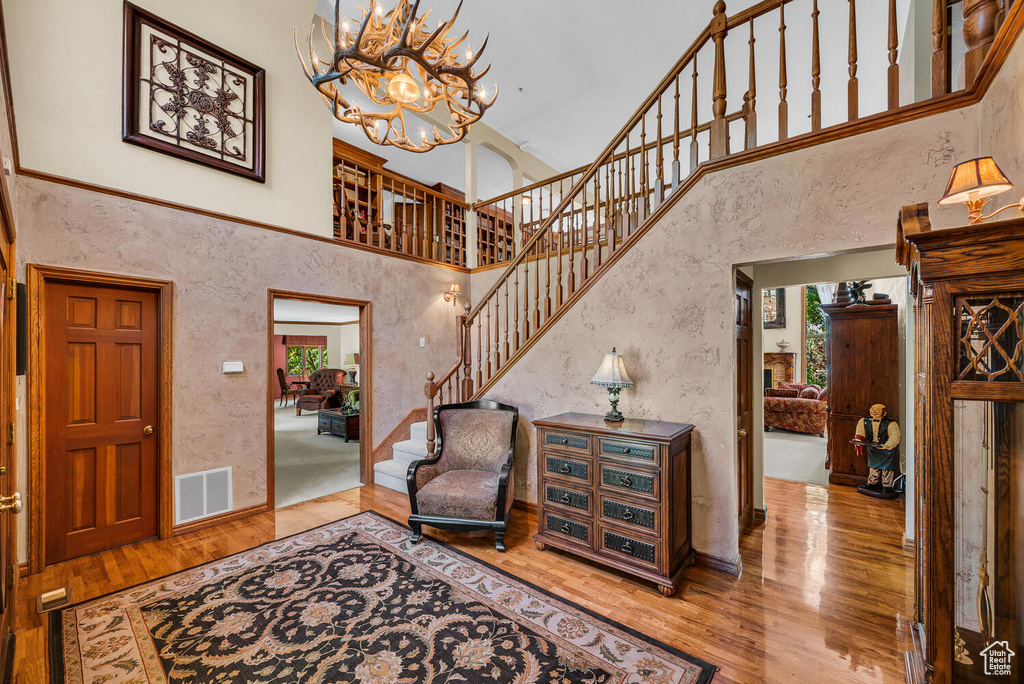 Foyer with hardwood / wood-style floors, a high ceiling, a chandelier, stairs, and baseboards