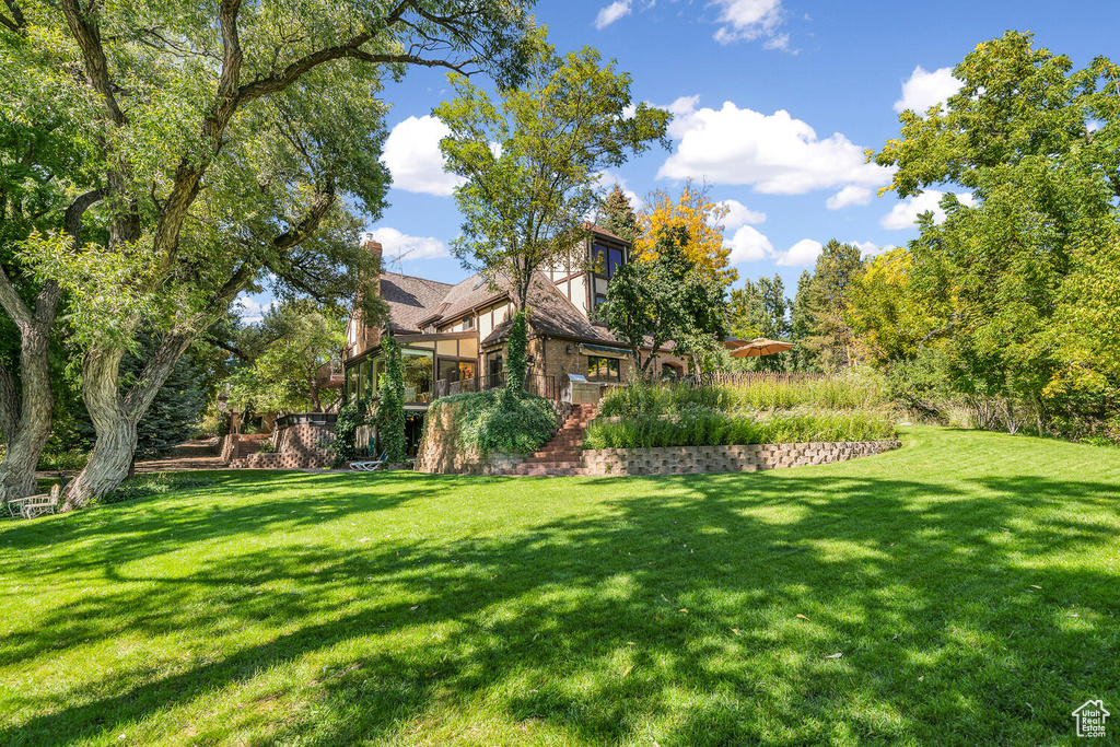 View of green lawn featuring a sunroom and stairs