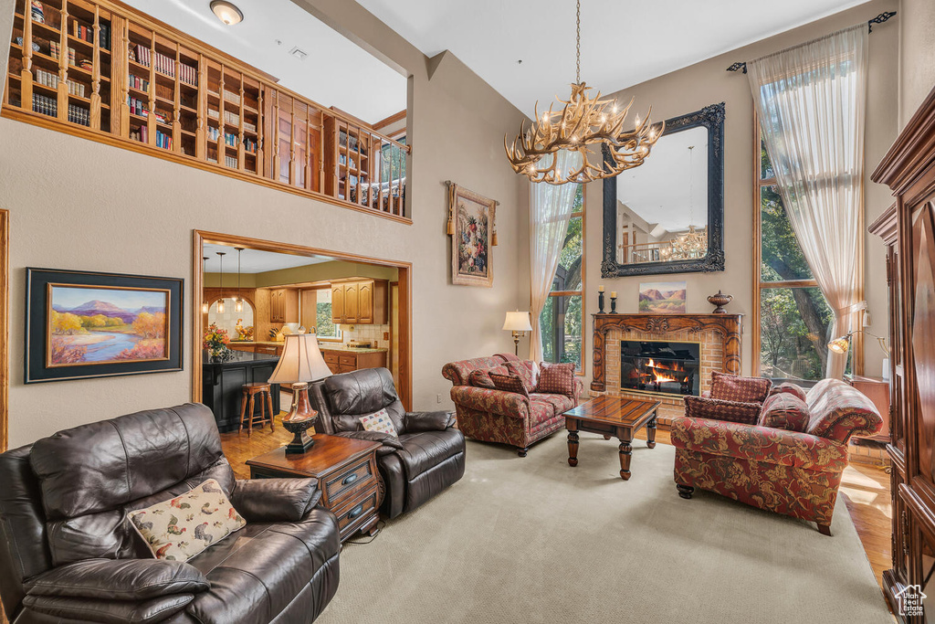 Carpeted living room featuring a chandelier, a glass covered fireplace, and healthy amount of natural light