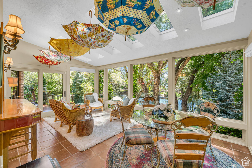 Sunroom with a skylight, tile patterned flooring, and vaulted ceiling