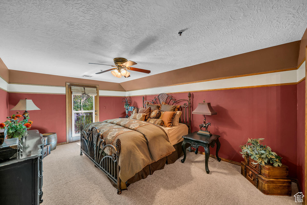 Bedroom with light colored carpet, a textured ceiling, a ceiling fan, and access to exterior